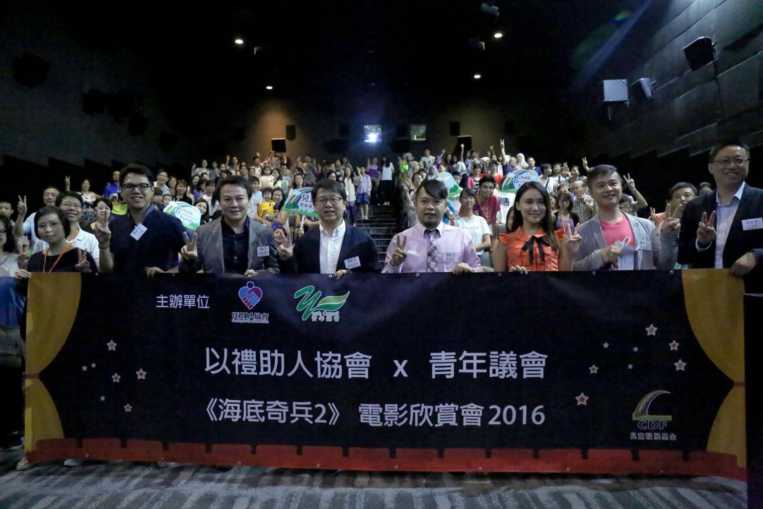 兒童、家長及義工在戲院手持活動橫額合照。